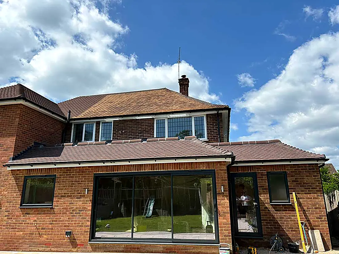 The rear of a brick house with a tiled extension roof over bifold doors