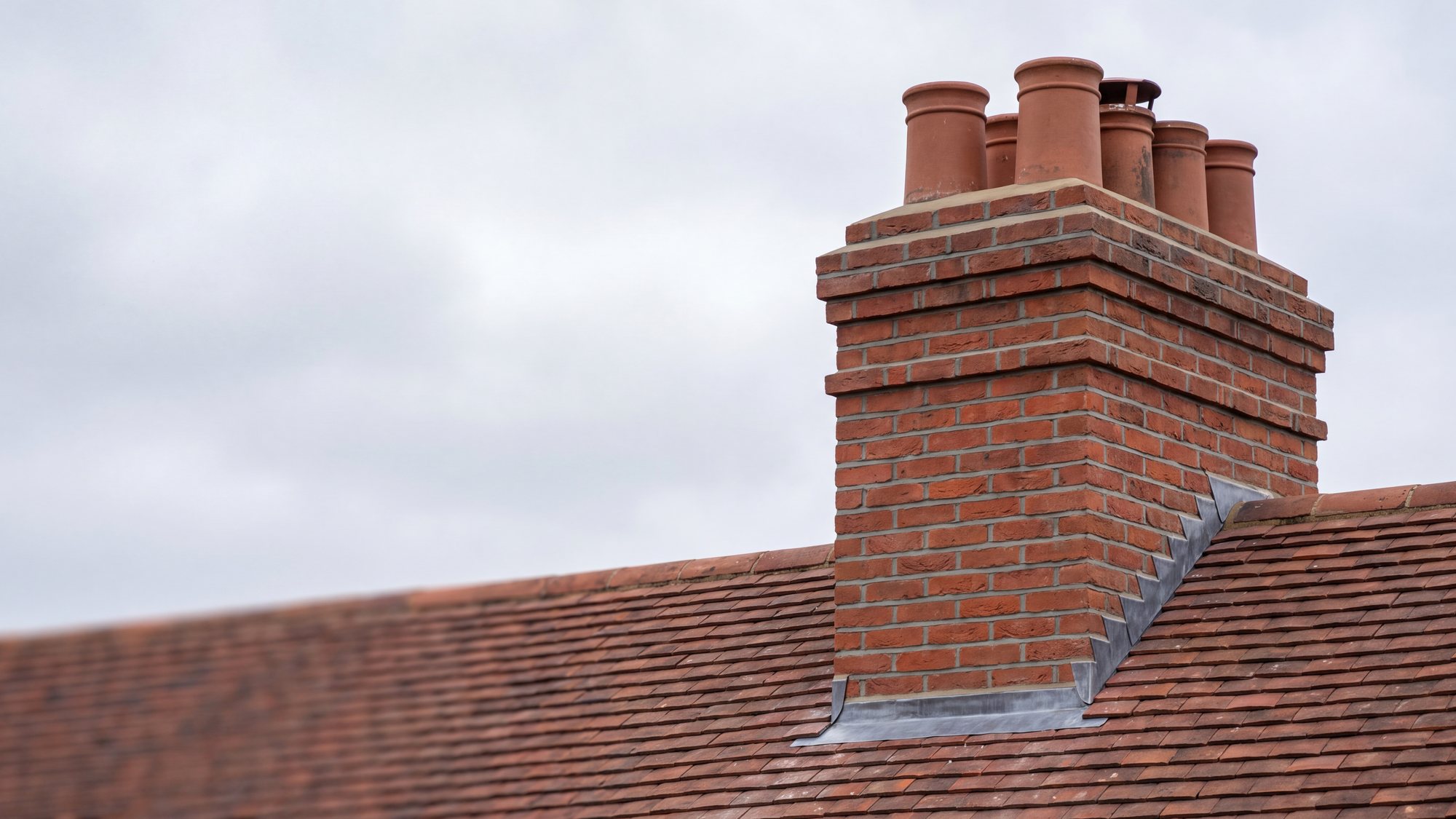 A repointed Victorian brick chimney stack with fresh mortar and new lead flashing