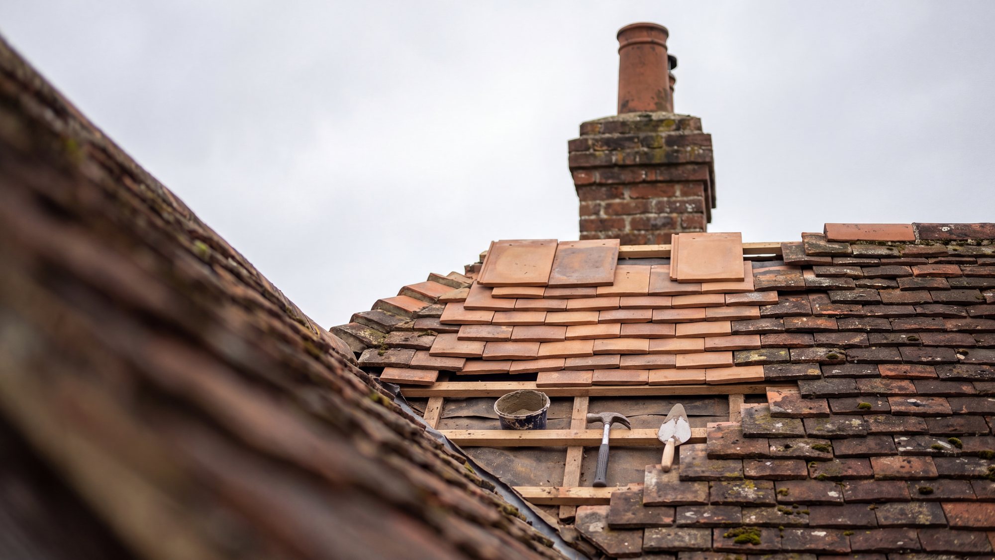 A British pitched tile roof part way through a repair, with replacement tiles in place