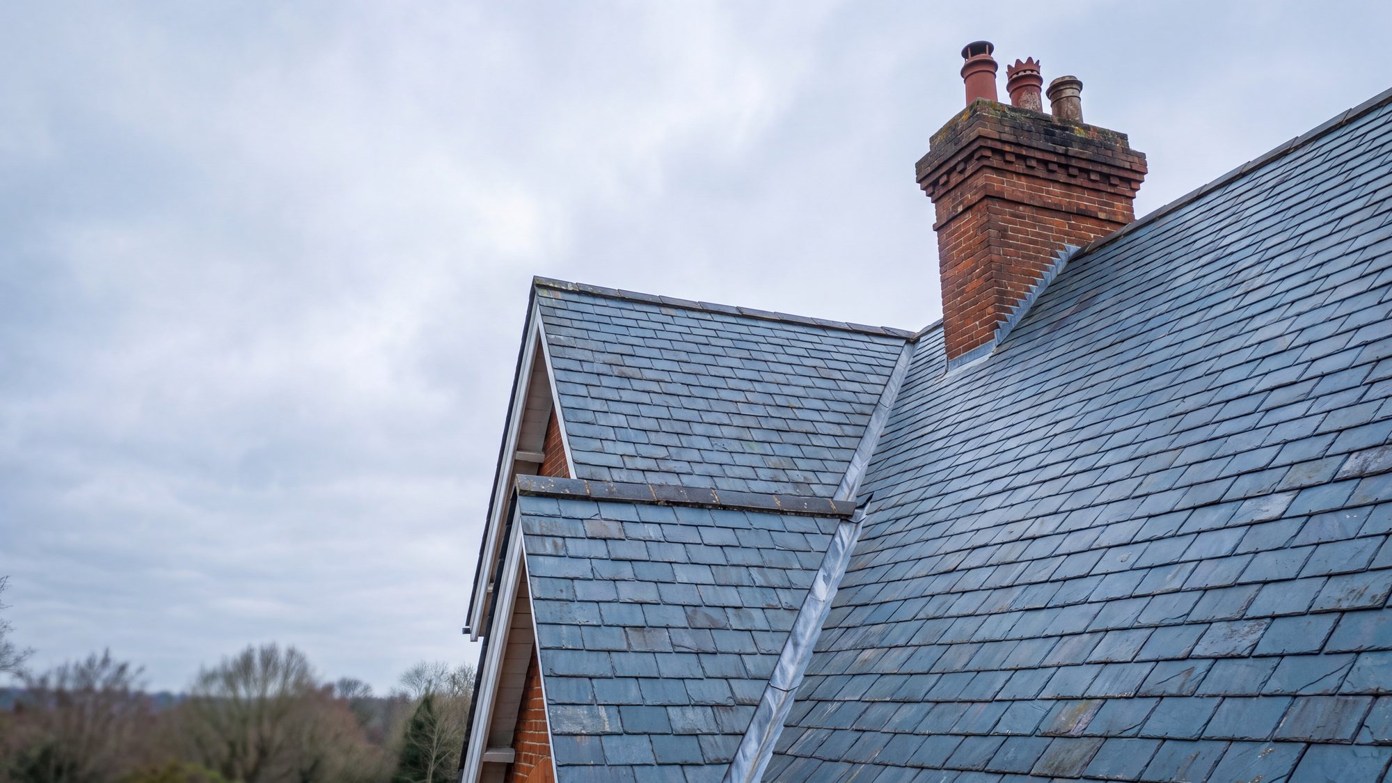 A steeply pitched roof in natural blue grey slate with a lead valley between two slopes