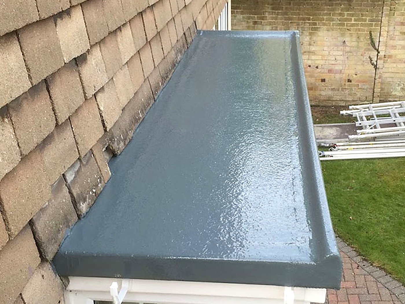After: the same porch roof finished in grey fibreglass with a clean new trim