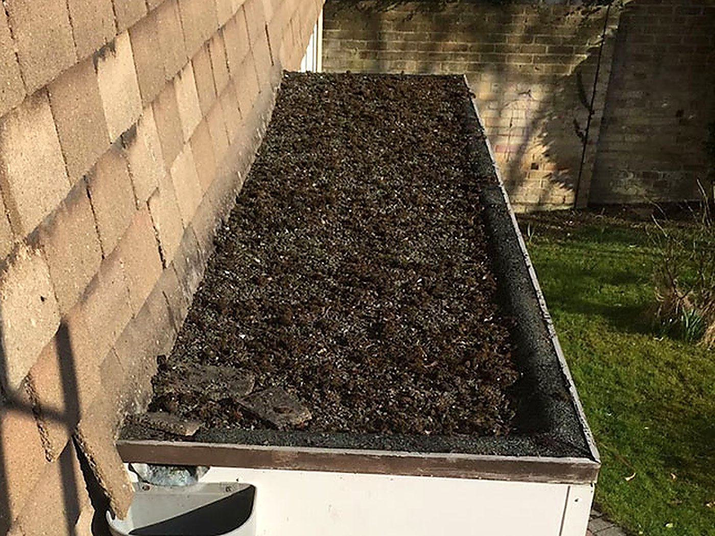 Before: the old felt porch roof covered in moss and debris, with a tired gutter