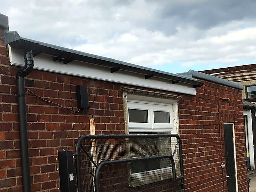 White uPVC fascia and soffit with a black downpipe on a brick wall