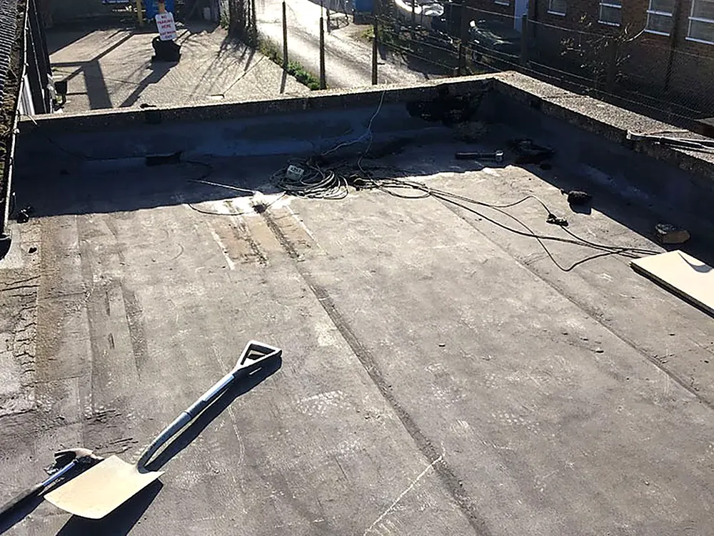 A felt flat roof part way through being laid, tools on the deck